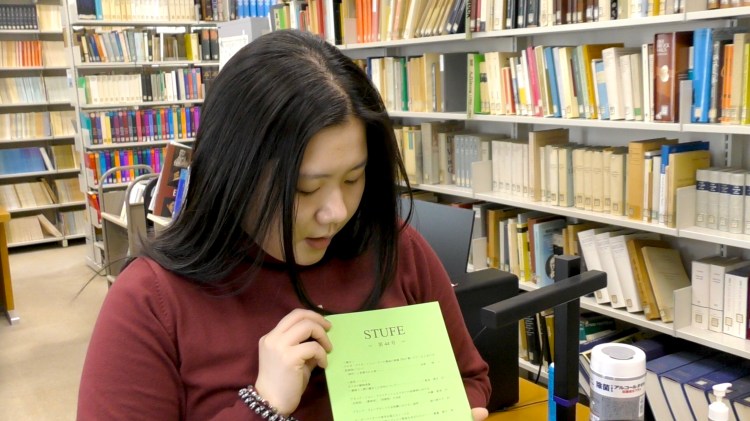 ドイツ文学専攻院生室_"STUFE"を手に取る田中さん